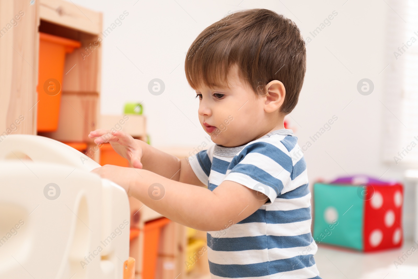 Photo of Cute little child playing in modern playpen at home