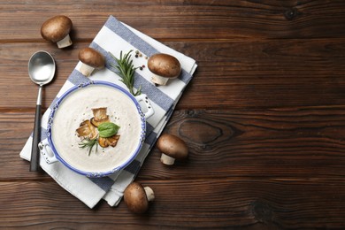 Photo of Delicious homemade mushroom soup served on wooden table, flat lay. Space for text
