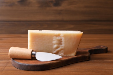 Delicious parmesan cheese with knife on wooden table