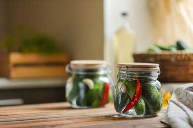 Photo of Jar of pickled cucumbers on wooden table. Space for text