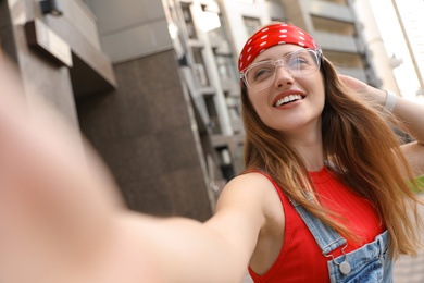 Photo of Beautiful young woman in stylish  headband taking selfie outdoors