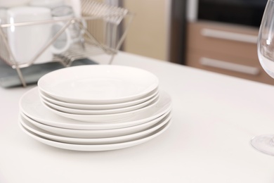 Photo of Stack of clean dishes on table in kitchen. Space for text