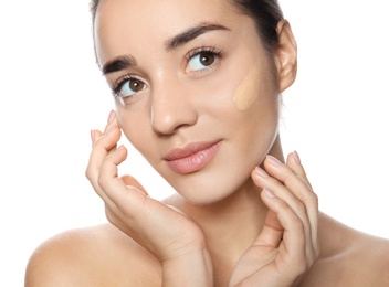 Portrait of young woman with liquid foundation on her face against white background