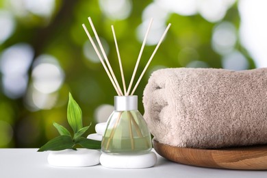 Image of Composition with towel, air freshener and spa stones against blurred green background