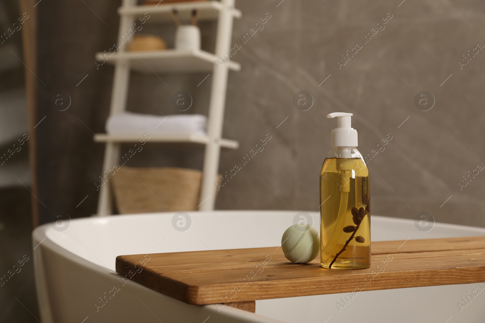 Photo of Wooden tray with bottle of shower gel and bath bomb on tub indoors, space for text