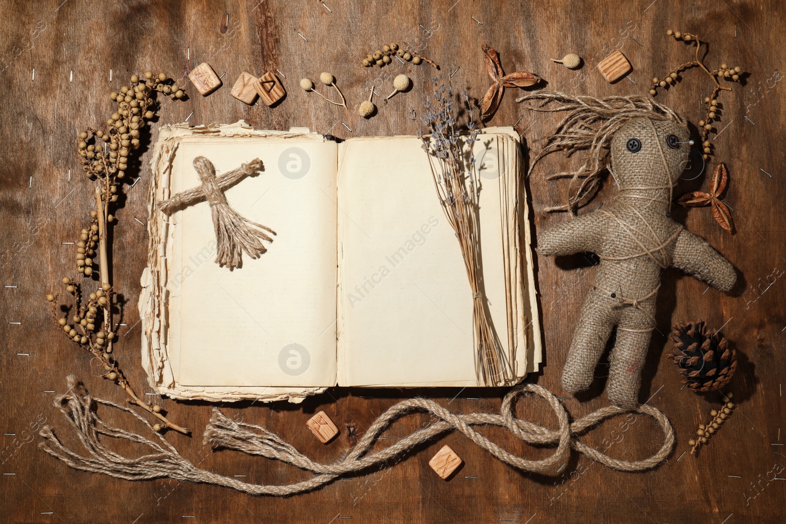 Photo of Female voodoo dolls with pins surrounded by ceremonial items on wooden background, flat lay