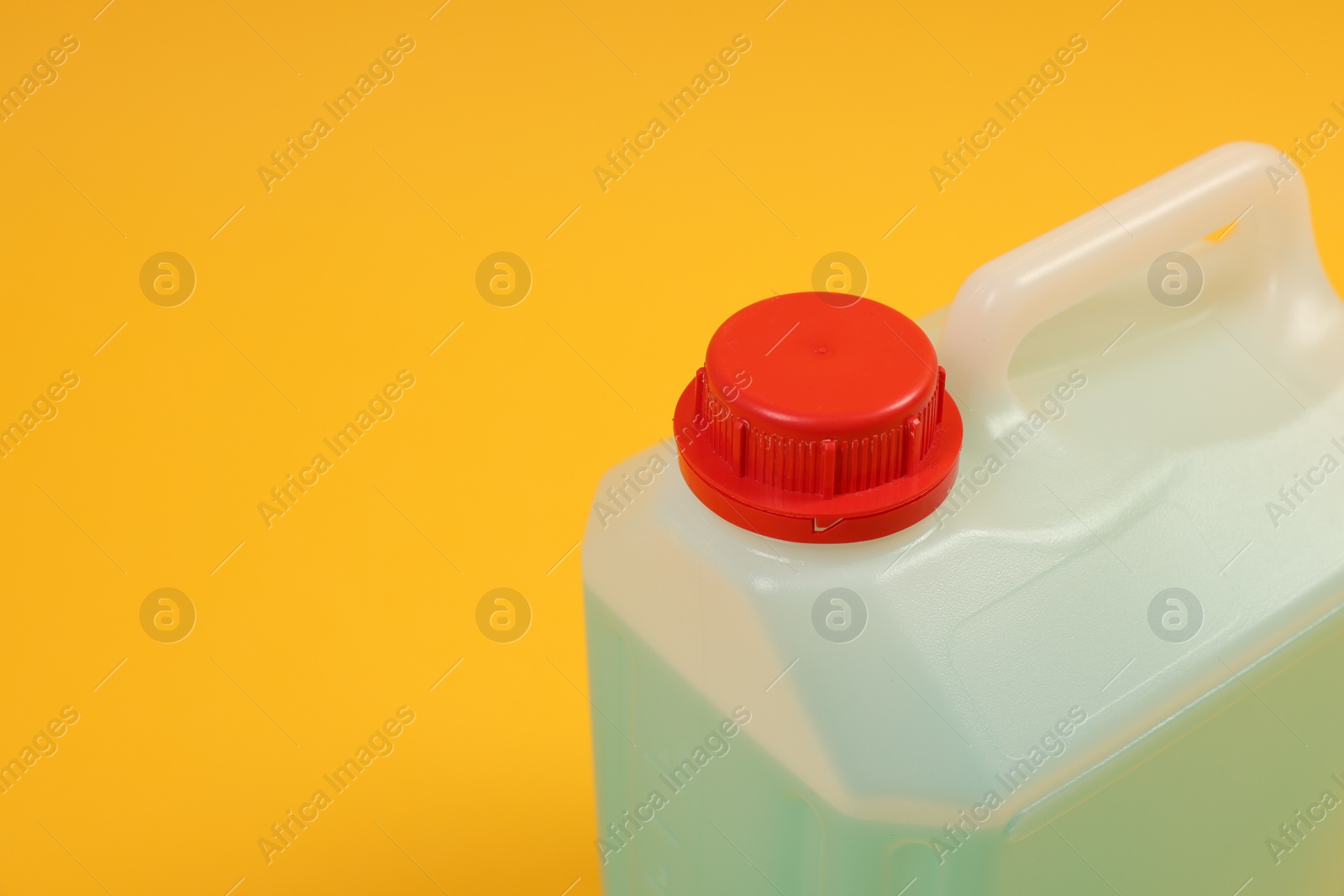 Photo of Plastic canister with green liquid on orange background, closeup. Space for text