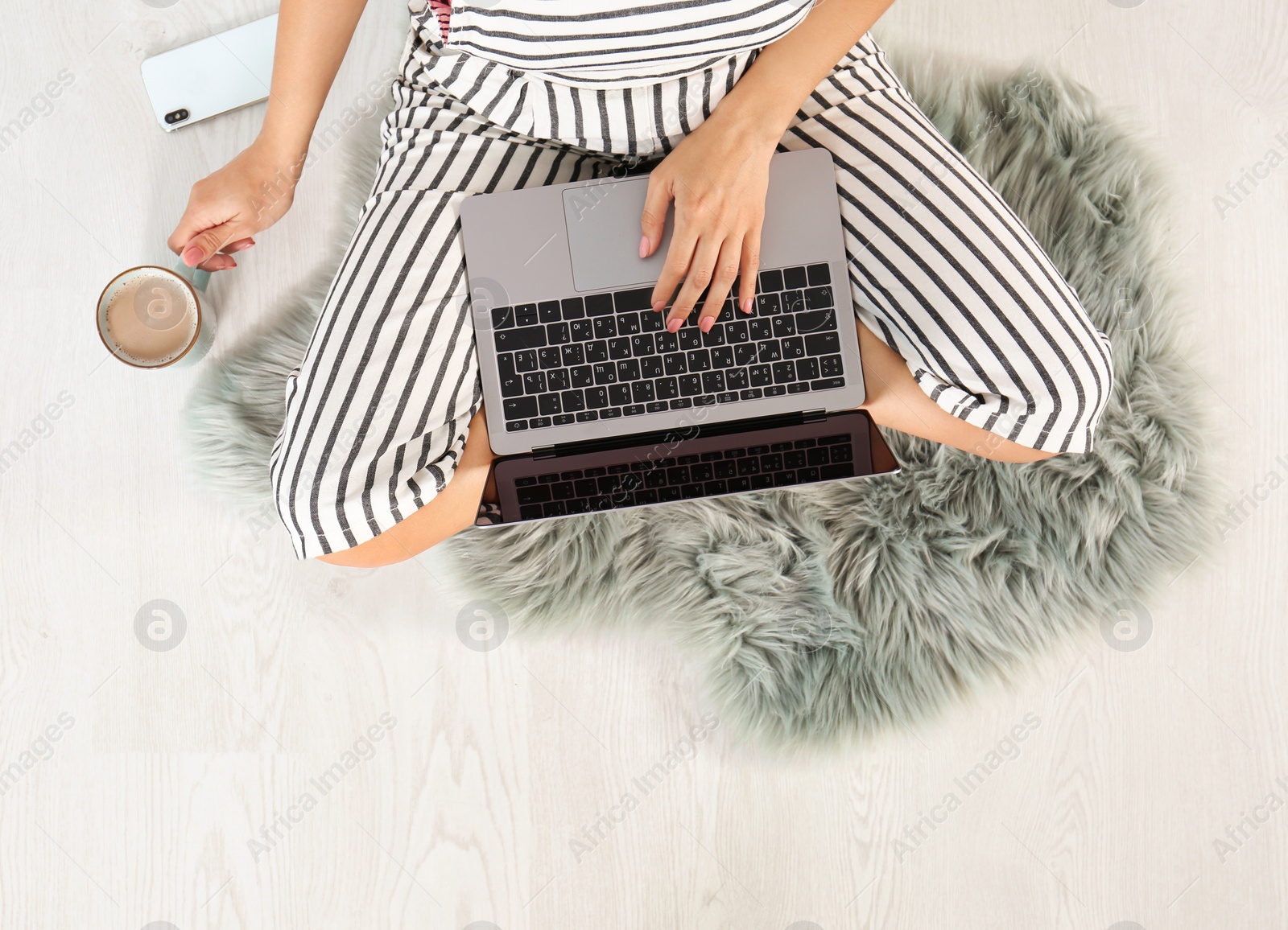 Photo of Young woman with cup of coffee and laptop sitting on floor, top view