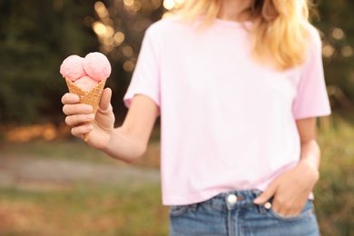 Woman with delicious ice cream in waffle cone outdoors, closeup