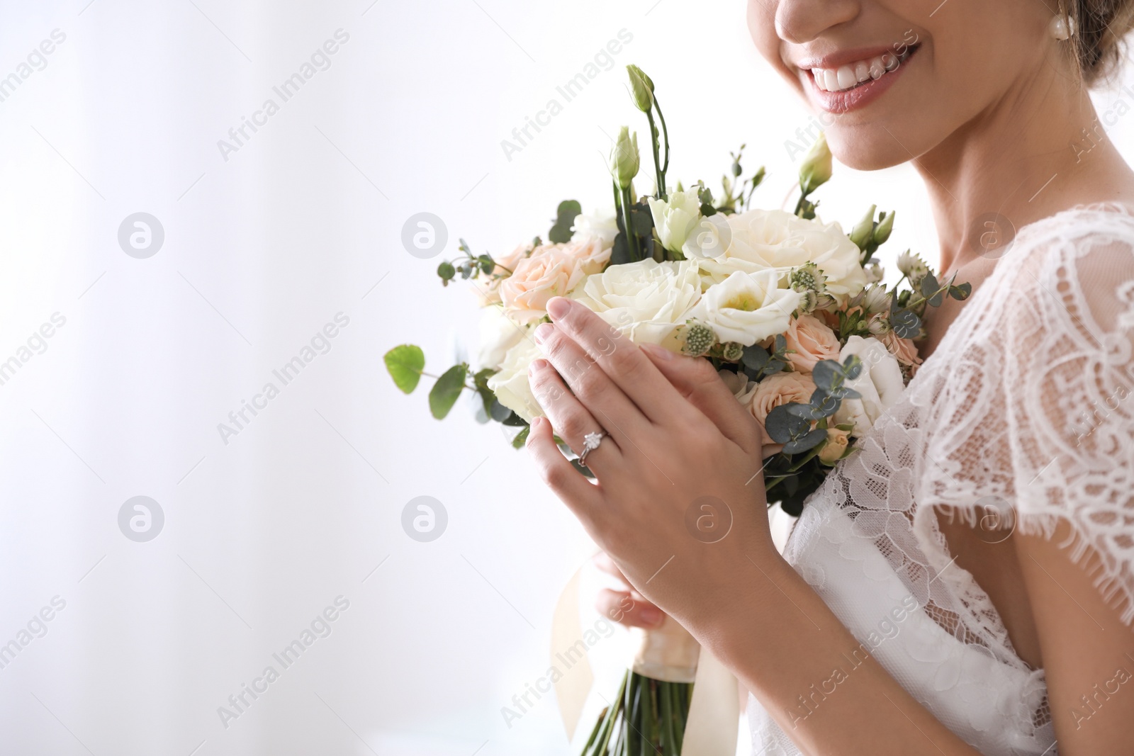 Photo of Young bride with beautiful wedding bouquet on blurred background, closeup. Space for text