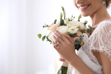 Young bride with beautiful wedding bouquet on blurred background, closeup. Space for text