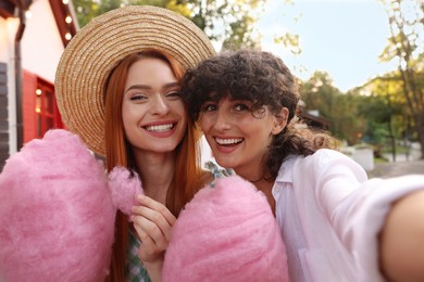 Happy friends with cotton candies taking selfie outdoors