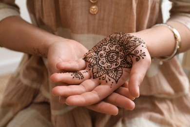 Woman with henna tattoo on palm, closeup. Traditional mehndi ornament