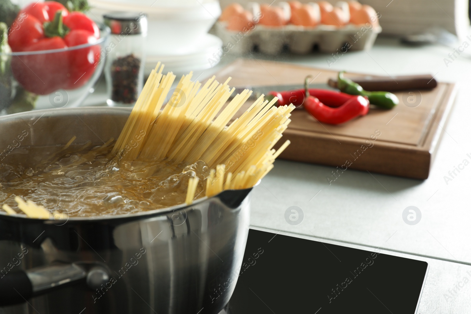 Photo of Cooking spaghetti in pot on electric stove, closeup. Space for text