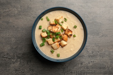 Photo of Bowl of fresh homemade mushroom soup on gray background, top view