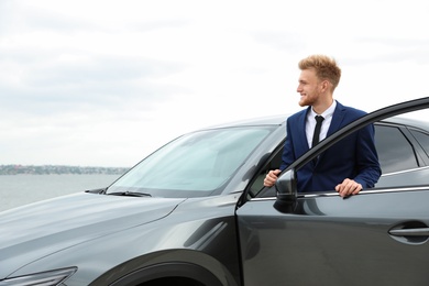 Photo of Young successful man near modern car outdoors