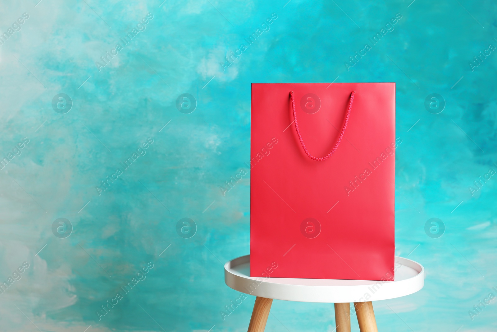 Photo of Mockup of paper shopping bag on table against color background