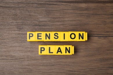 Photo of Yellow cubes with phrase Pension Plan on wooden table, flat lay