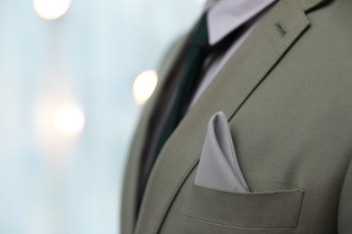 Photo of Man with handkerchief in suit pocket against blurred lights, closeup. Space for text