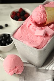 Delicious ice cream in container and wafer cone on white table