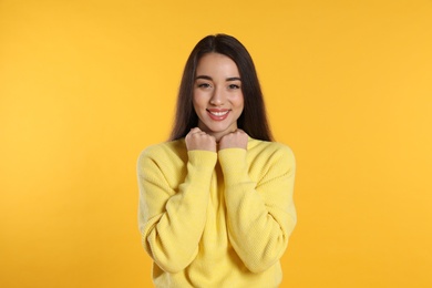 Photo of Beautiful young woman wearing warm sweater on yellow background