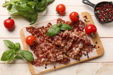 Photo of Slices of tasty fried bacon with different spices and tomatoes on wooden table, flat lay