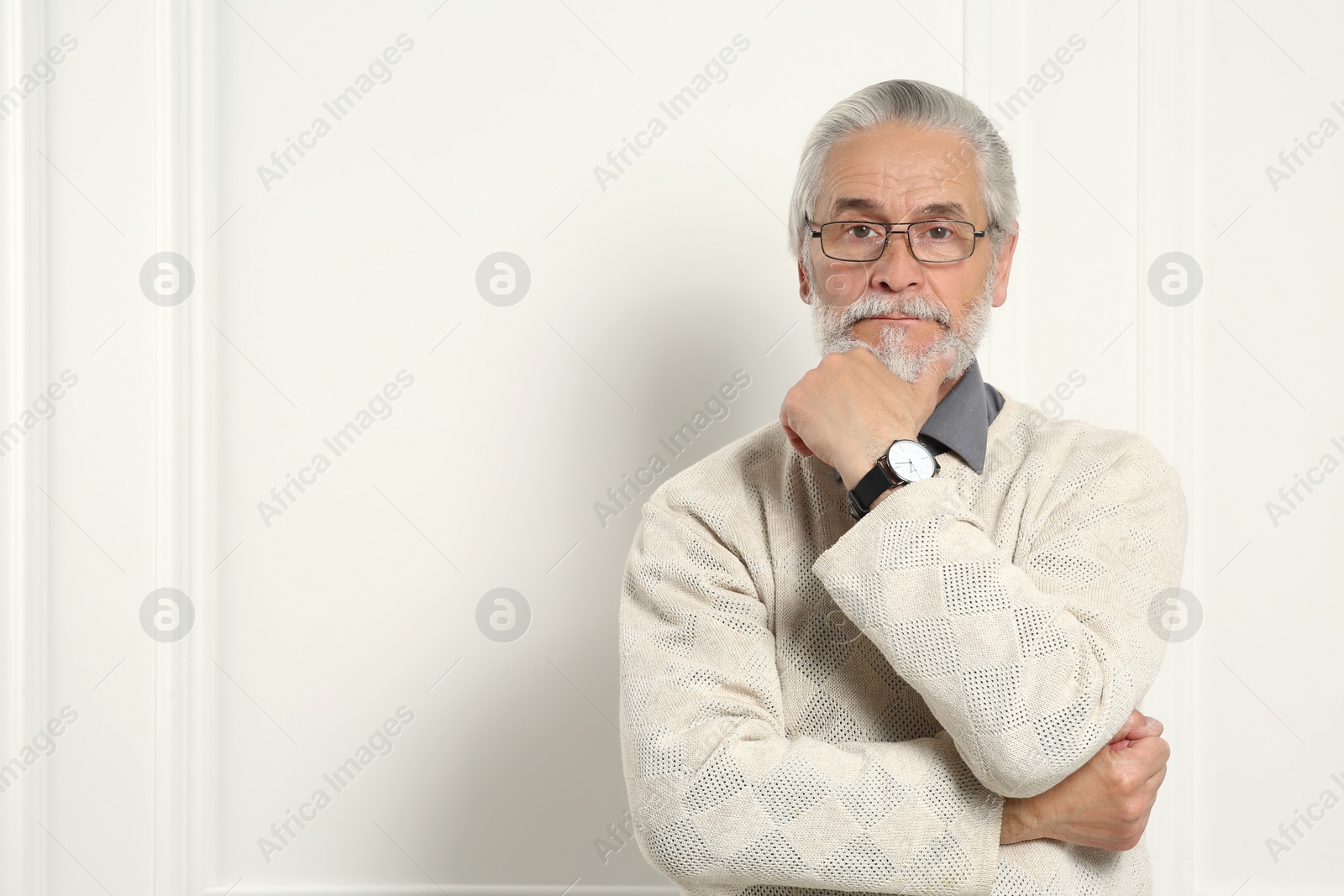 Photo of Portrait of handsome senior man in eyeglasses near white wall. Space for text