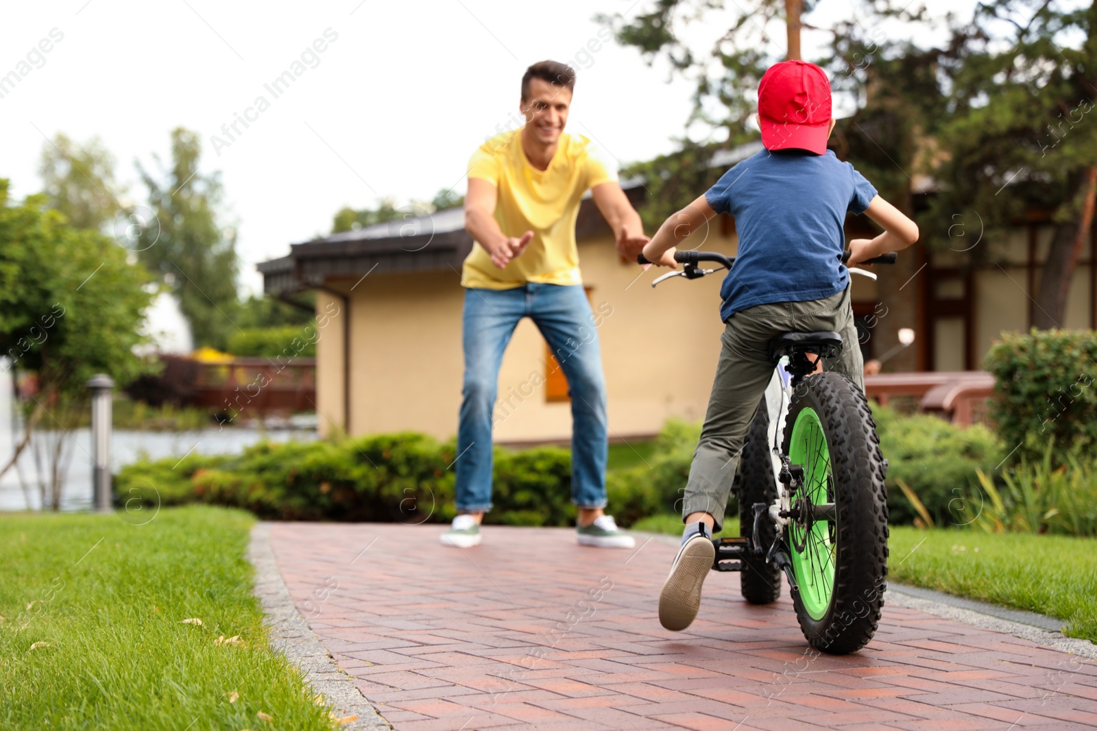 Photo of Dad teaching son to ride bicycle outdoors