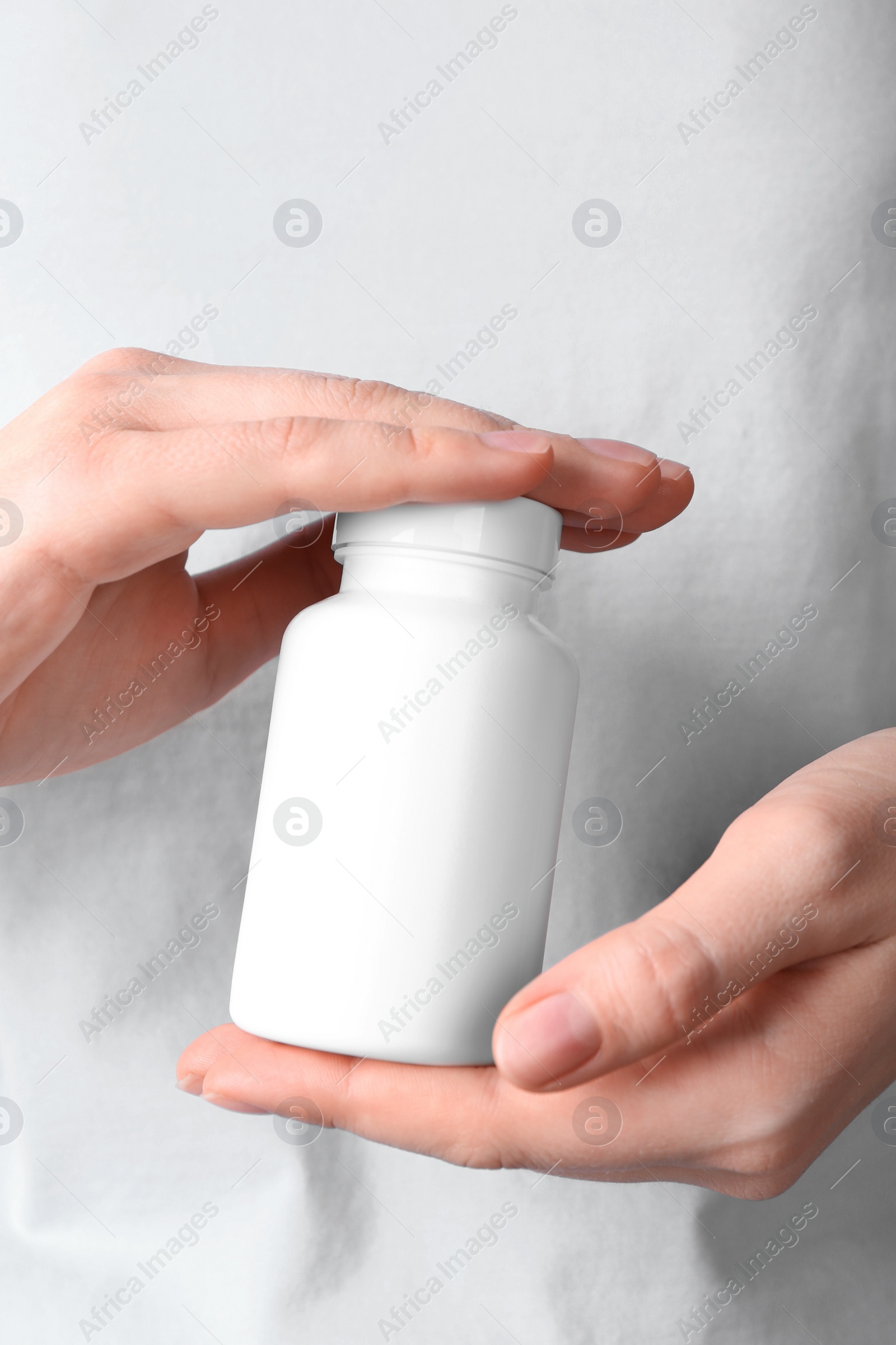 Photo of Woman holding one white pill bottle, closeup