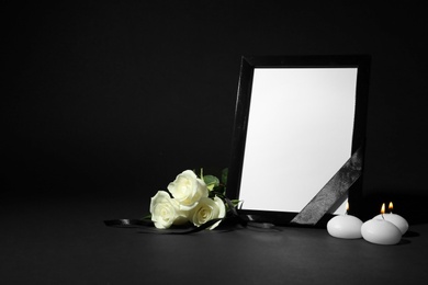 Funeral photo frame with ribbon, white roses and candles on black background. Space for design