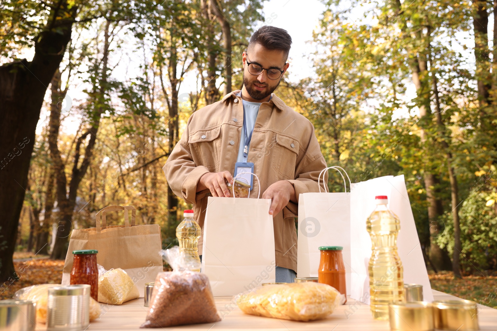 Photo of Volunteer packing food products at table in park