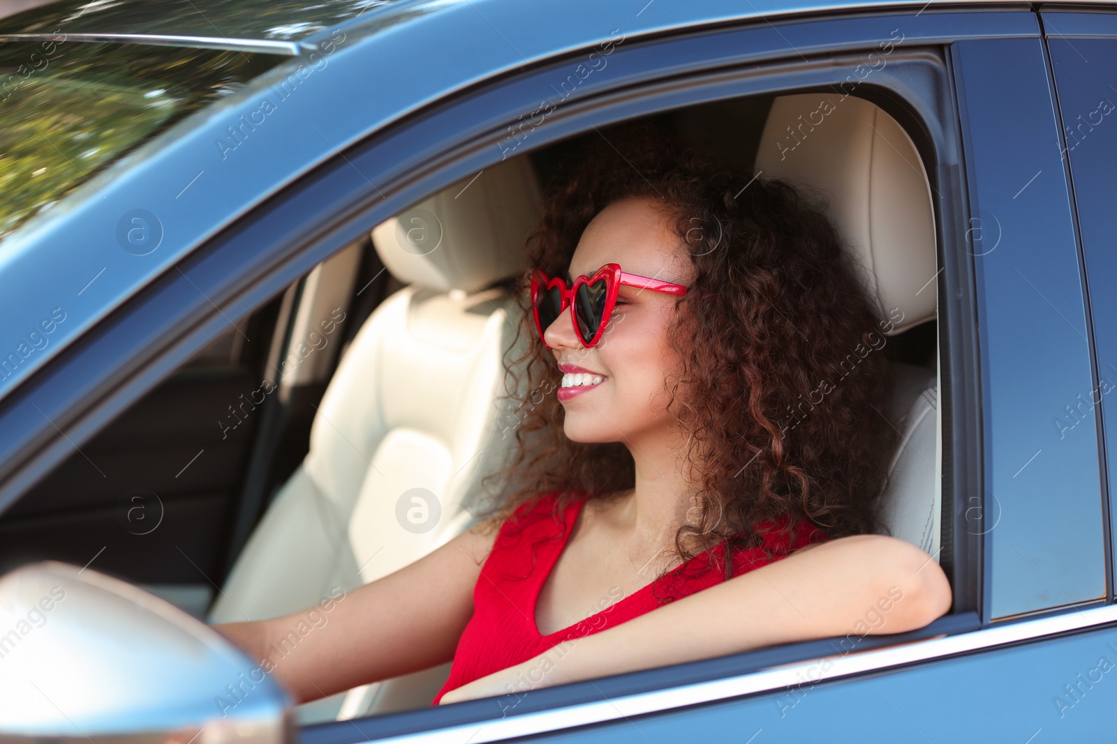 Photo of Young beautiful African-American woman wearing heart shaped glasses in car