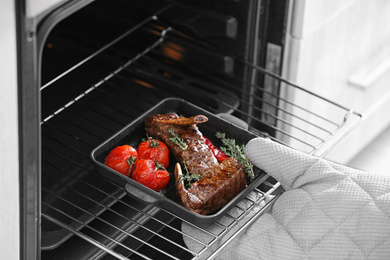 Chef taking delicious roasted ribs out of oven, closeup