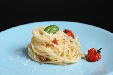 Photo of Tasty spaghetti with tomatoes and cheese on plate against black background, closeup. Exquisite presentation of pasta dish