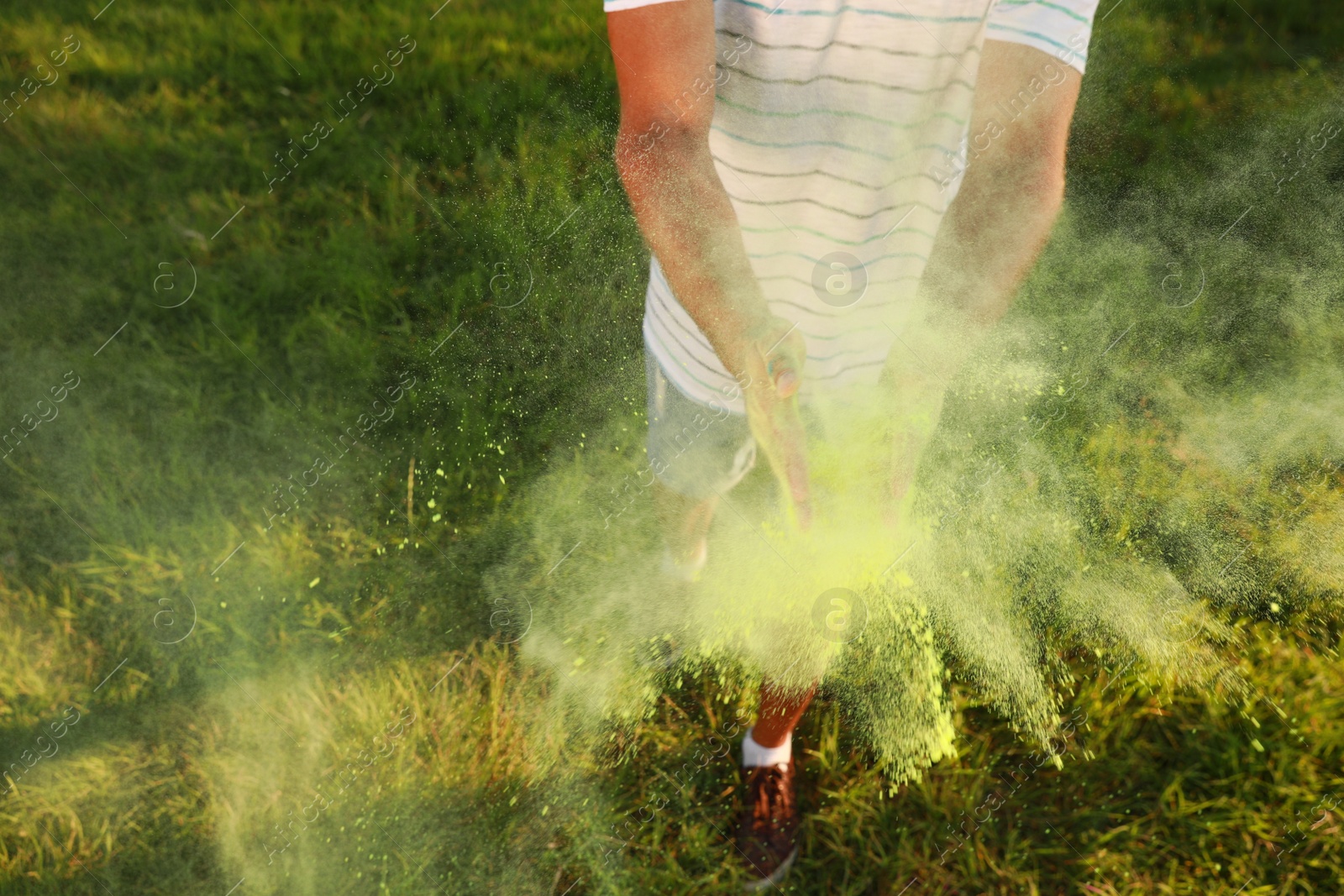 Photo of Man with green powder dye outdoors, closeup. Holi festival celebration