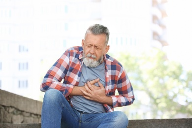 Photo of Mature man having heart attack, outdoors