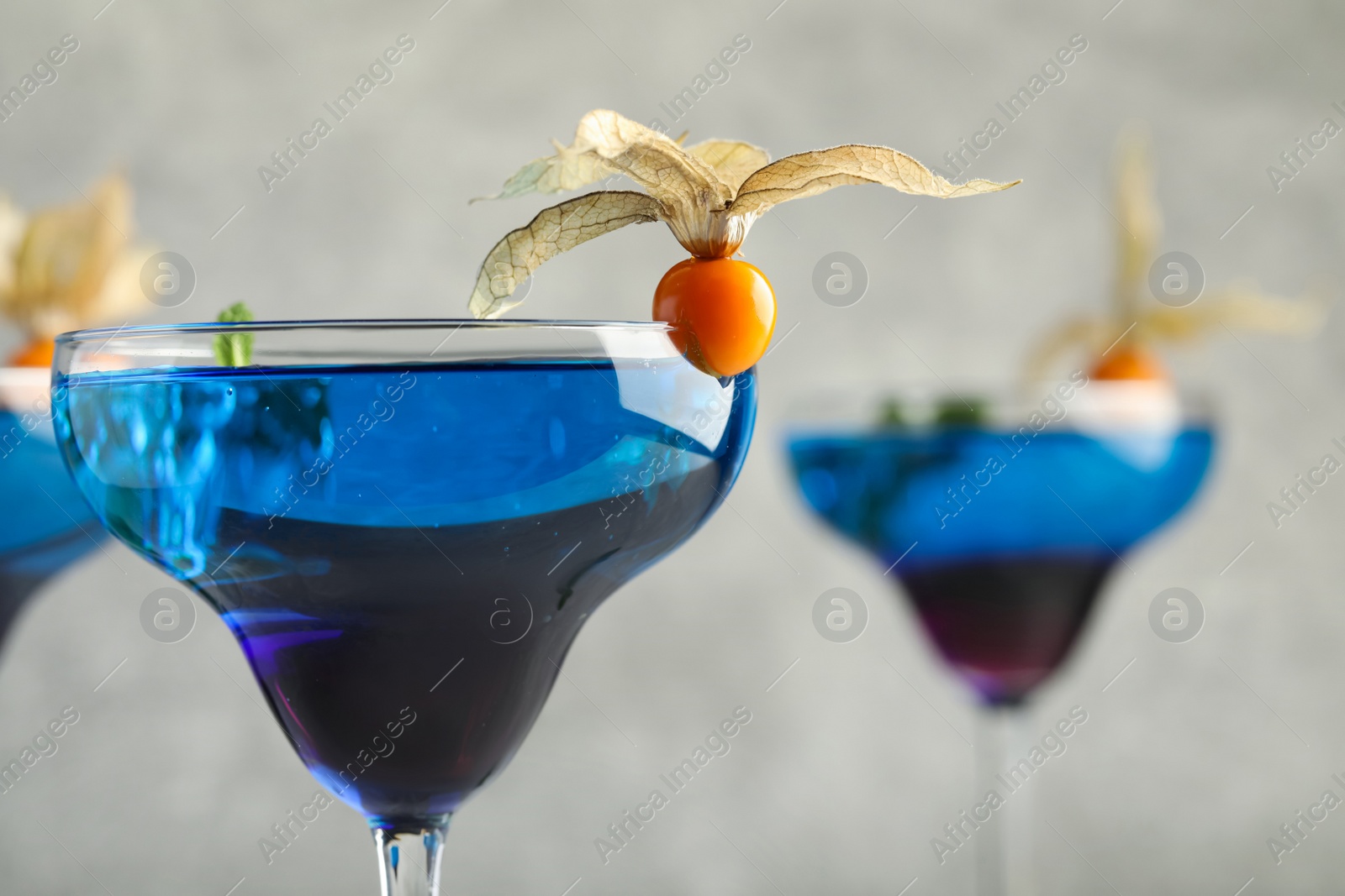 Photo of Tasty cocktail decorated with physalis fruit on grey background, closeup. Space for text