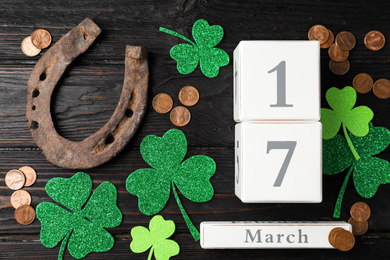 Photo of Flat lay composition with horseshoe and block calendar on black wooden background. St. Patrick's Day celebration