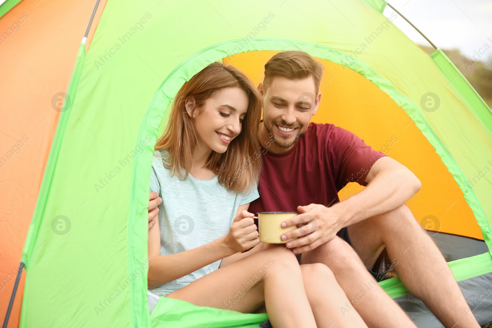 Photo of Young woman with mug and man in camping tent