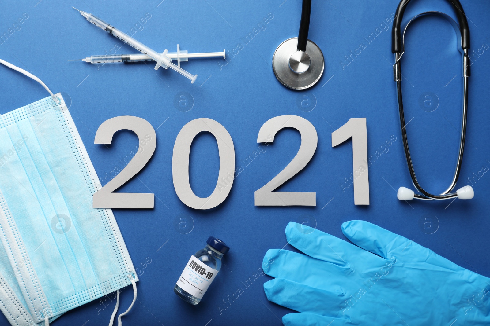 Photo of Flat lay composition with coronavirus vaccine and number 2021 on blue background