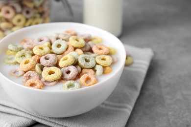 Photo of Tasty colorful cereal rings and milk in bowl on grey table, closeup. Space for text