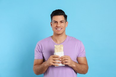 Man with delicious shawarma on turquoise background