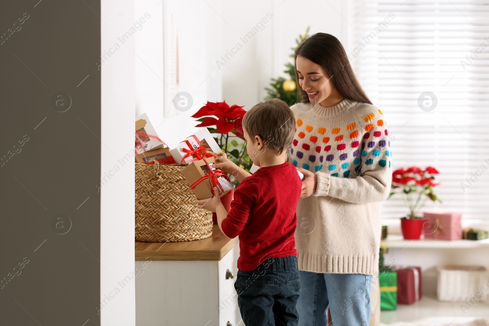 Photo of Mother and son with Christmas gifts at home. Advent calendar in basket