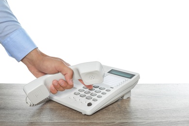 Photo of Man dialing number on telephone at table against white background, closeup