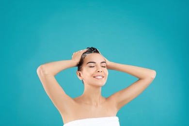 Photo of Beautiful young woman washing hair on light blue background