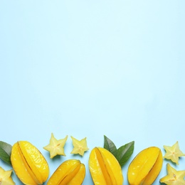 Photo of Delicious carambola fruits on light blue background, flat lay. Space for text