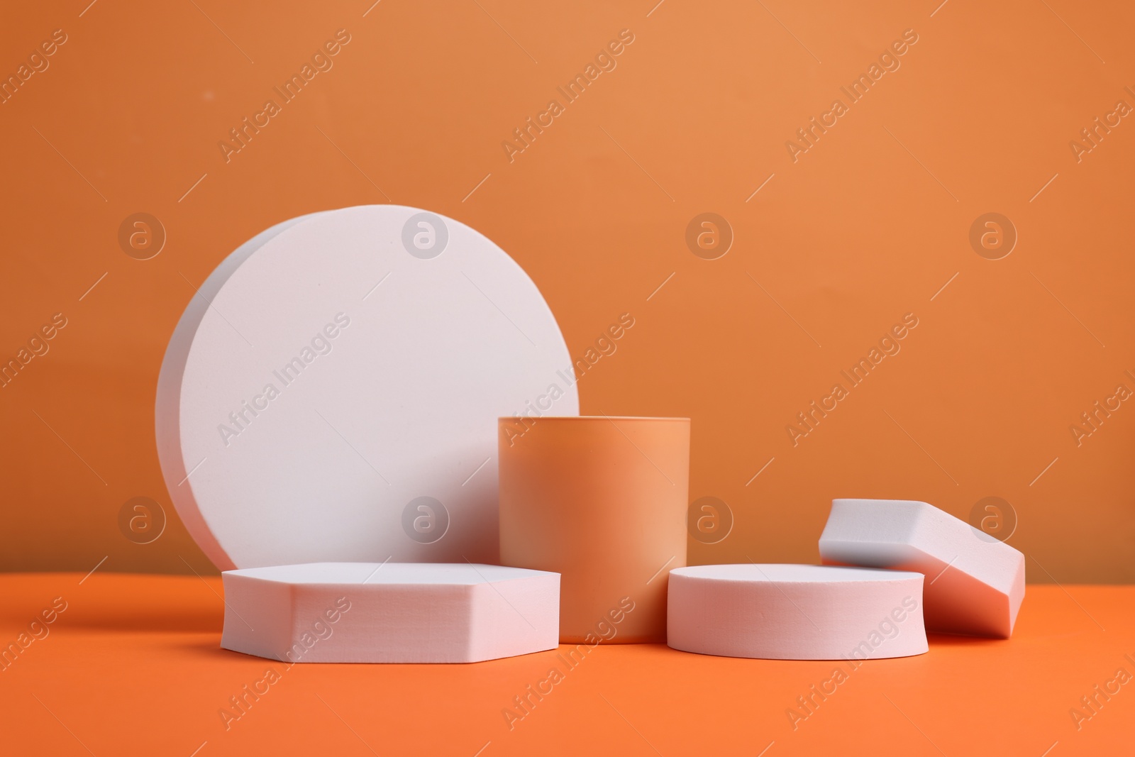 Photo of Scene for product presentation. Podiums of different geometric shapes on orange background