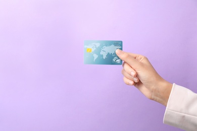 Woman holding credit card on color background