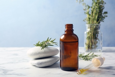 Photo of Composition with bottle of rosemary oil and fresh twigs on light table