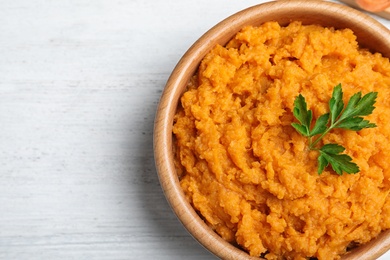 Photo of Bowl with mashed sweet potatoes on wooden table, top view. Space for text